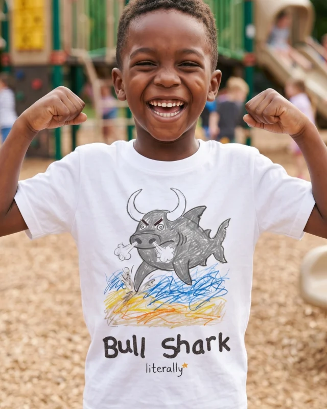 Boy flexing at a playground wearing the white literally Bull Shark sketch t-shirt