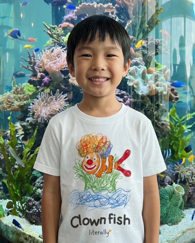 Boy at an aquarium wearing the white literally Clownfish sketch t-shirt